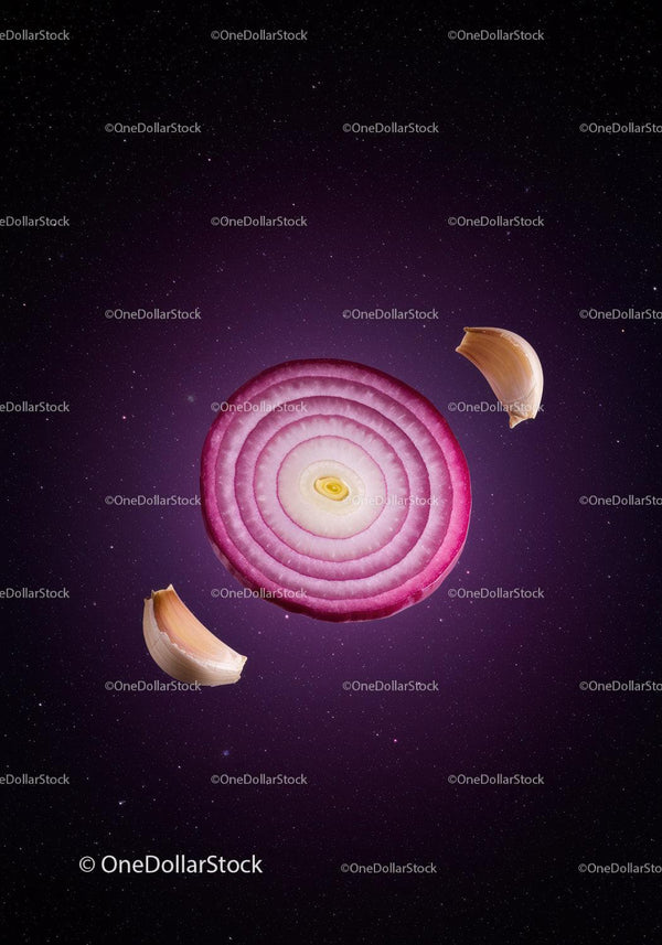 Red onion slice surrounded by garlic cloves on dark background