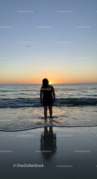 Silhouette of Woman Standing in Ocean During Sunset