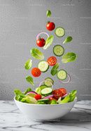 Fresh vegetable salad ingredients falling into bowl