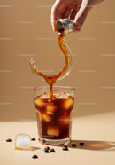 Pouring cold brew coffee over ice cubes in glass