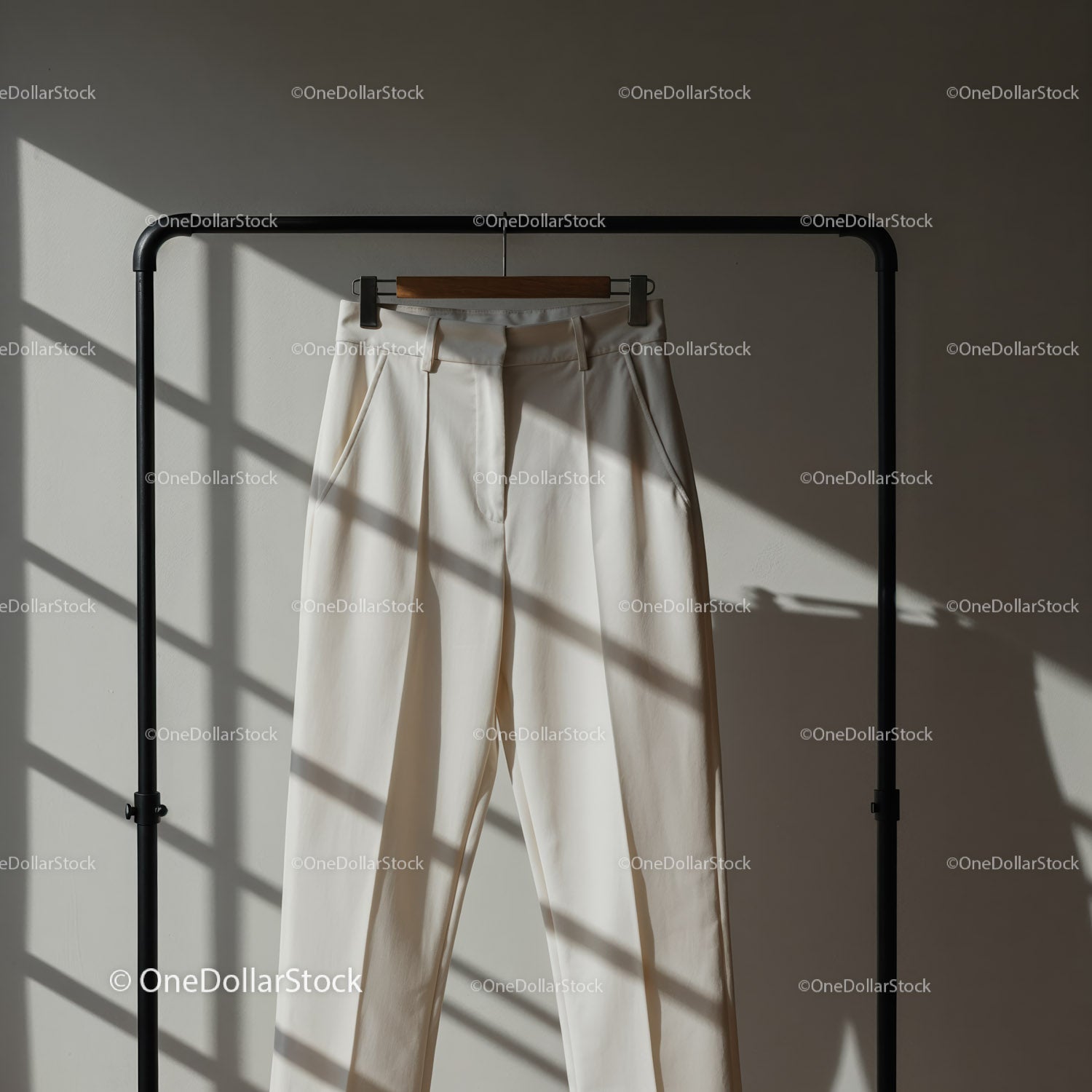Elegant white trousers hanging on black rack