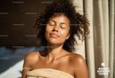Serene Woman with Curly Hair Enjoying Sunlight in Relaxing Spa