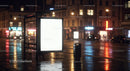 Illuminated Bus Stop Shelter with Advertising Screen on Rainy Night