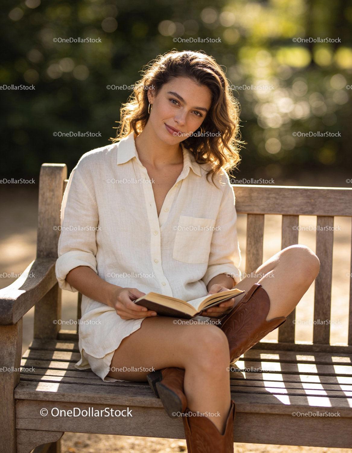 Young woman enjoying a book on a sunny bench