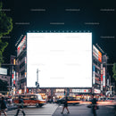 Busy city intersection with illuminated blank billboard at night