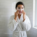 Woman Applying Facial Mask in Spa Setting for Skin Rejuvenation