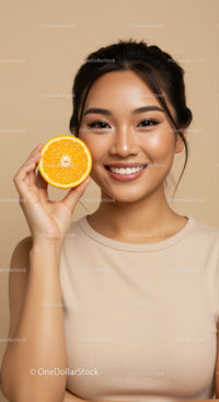 Smiling woman holding fresh orange slice in studio portrait