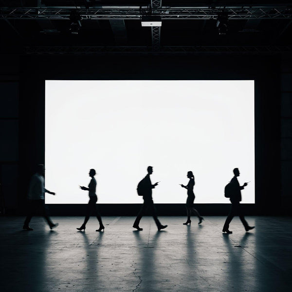 Silhouettes of people walking in front of large screen JPG Mockup Image