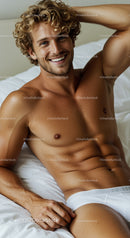 Smiling young man relaxing on bed in white underwear