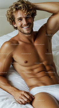 Smiling young man relaxing on bed in white underwear
