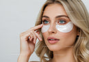 Young Woman Applying Skin Care Under Eye Patches with Blue Eyes