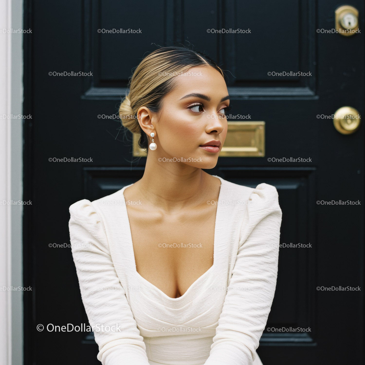 Elegancka kobieta w białej sukni pozuje przy czarnych drzwiach