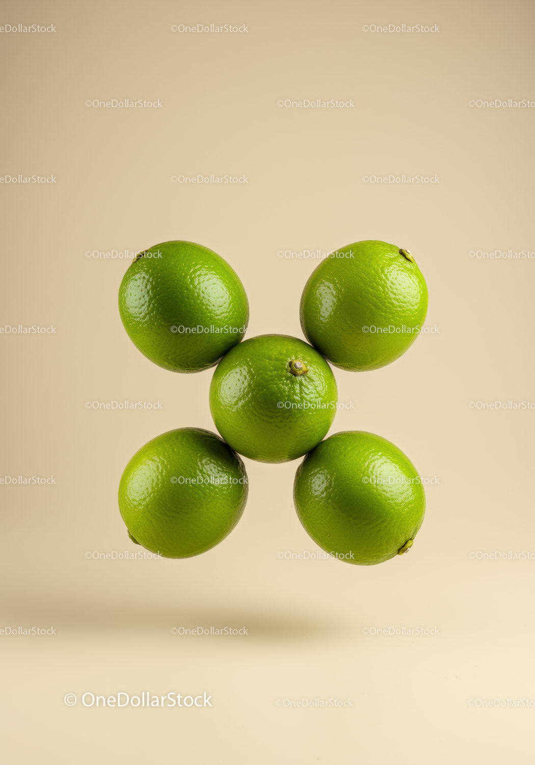 Five fresh green limes floating on beige background