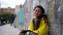 Young Woman in Yellow Jacket Smiling Near Graffiti Wall