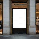 Empty illuminated billboard between fashion displays on street
