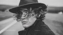 Young Man with Curly Hair and Styled Hat in Black and White Portrait