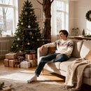 Young man relaxing on sofa near decorated Christmas tree