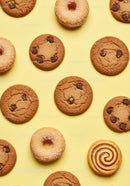 Assorted cookies and donuts on yellow background