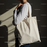 Person carrying plain eco friendly tote bag on shoulder