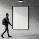 Man Walking Past Large Blank Poster on Concrete Wall