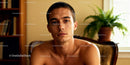 Thoughtful young man sitting indoors in warm light
