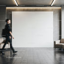 Blurred woman walking past blank wall in modern lobby