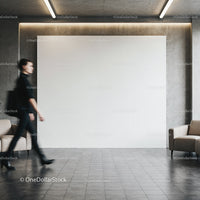 Blurred woman walking past blank wall in modern lobby