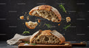Rustic sourdough bread torn with scattered rosemary leaves