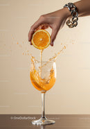 Hand squeezing fresh orange juice into wine glass