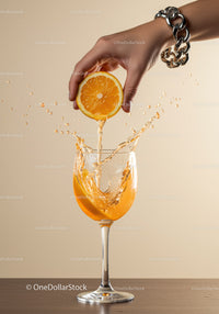 Hand squeezing fresh orange juice into wine glass
