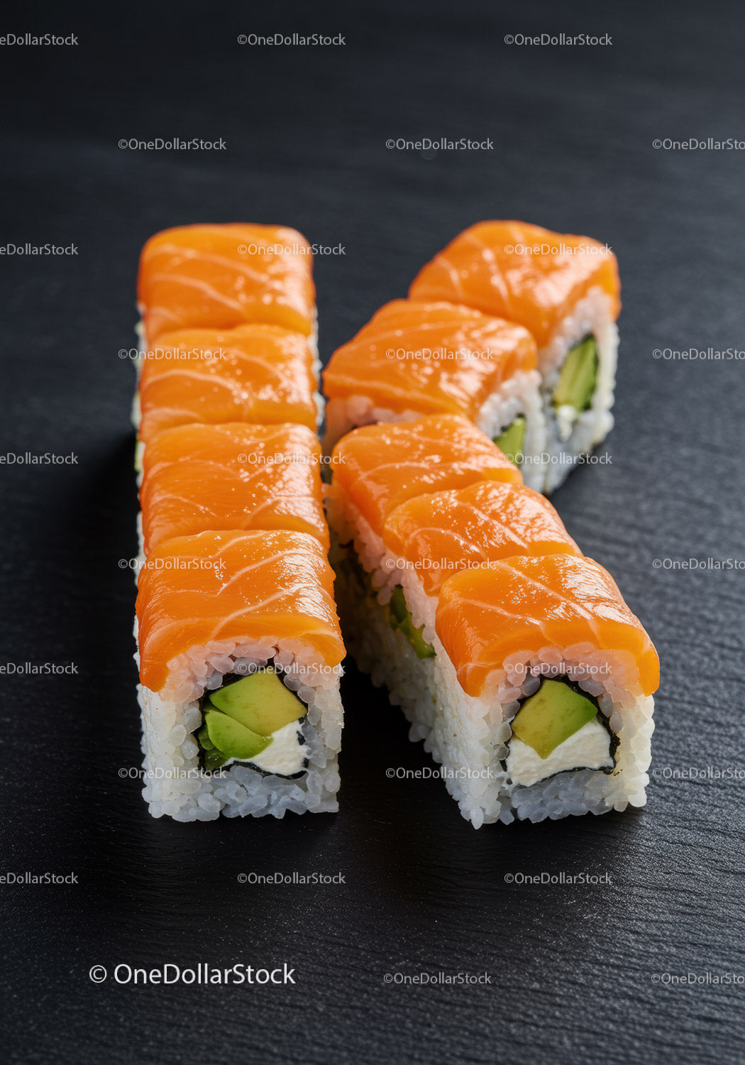 Fresh salmon avocado sushi rolls on dark slate surface
