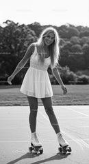 Young woman roller skating outdoors in white dress