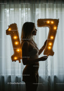Silhouette of woman holding glowing number balloons seventeen