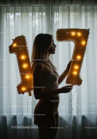 Silhouette of woman holding glowing number balloons seventeen