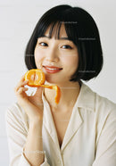 Portrait of a Young Woman Holding a Peeled Orange with a Bright Smile