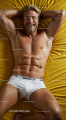 Smiling muscular man relaxing on yellow bed linen