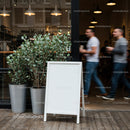 Blank white sandwich board outside modern cafe entrance