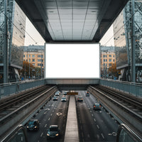 Urban highway beneath modern glass buildings with blank billboard