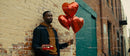 Man holding heart balloons and chocolates outdoors