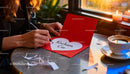 Writing a heartfelt love note on red card at cozy table