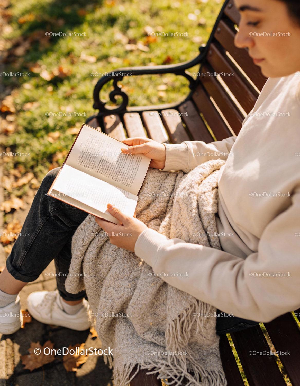 Woman Enjoying a Cozy Autumn Reading on Park Bench