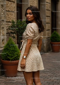Chic Woman in Floral Dress Posing Outdoors with City Background