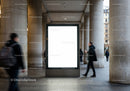 Blank illuminated billboard in urban colonnade walkway