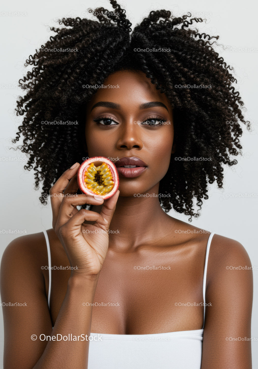 Portrait of a Young African American Woman with Curly Hair Holding Passion Fruit