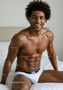 Smiling man with muscular build sitting on bed in white underwear