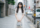 Elegant Young Woman in White Lace Dress on City Street