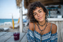 Young Woman with Curly Hair Smiling at Beachside Cafe During Summer