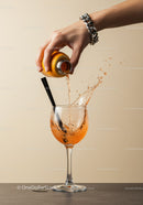 Pouring Orange Drink Into Wine Glass With Splash
