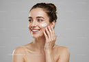 Young Woman Smiling Applying Facial Cream for Glowing Healthy Skin