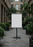 Blank whiteboard in urban courtyard surrounded by greenery